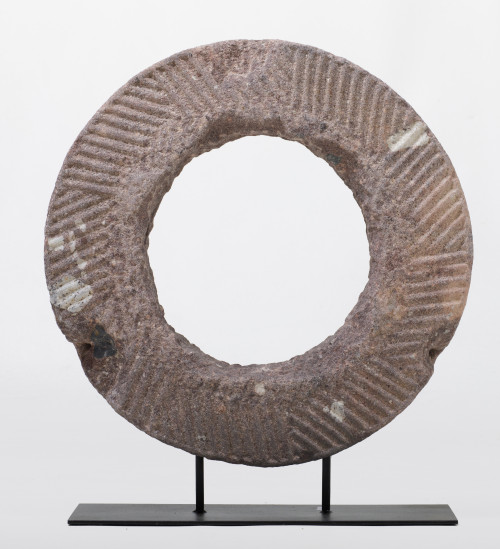 Escultura decorativa de piedra en forma de disco sobre pean